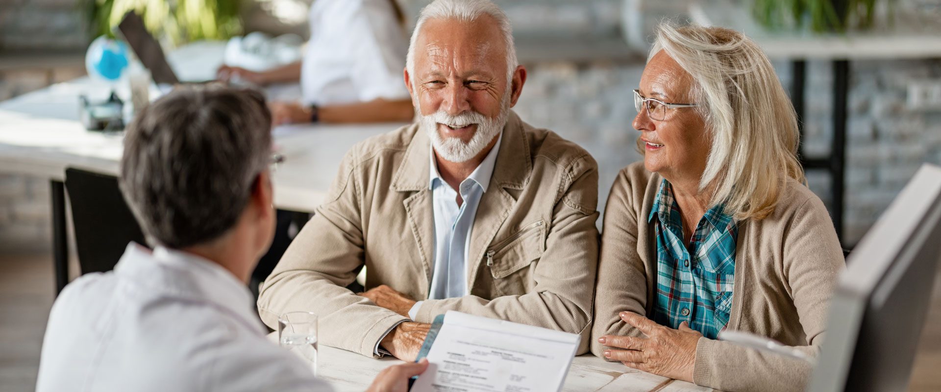happy-senior-couple-communicating-with-doctor-about-their-health-insurance-while-going-through-paperwork