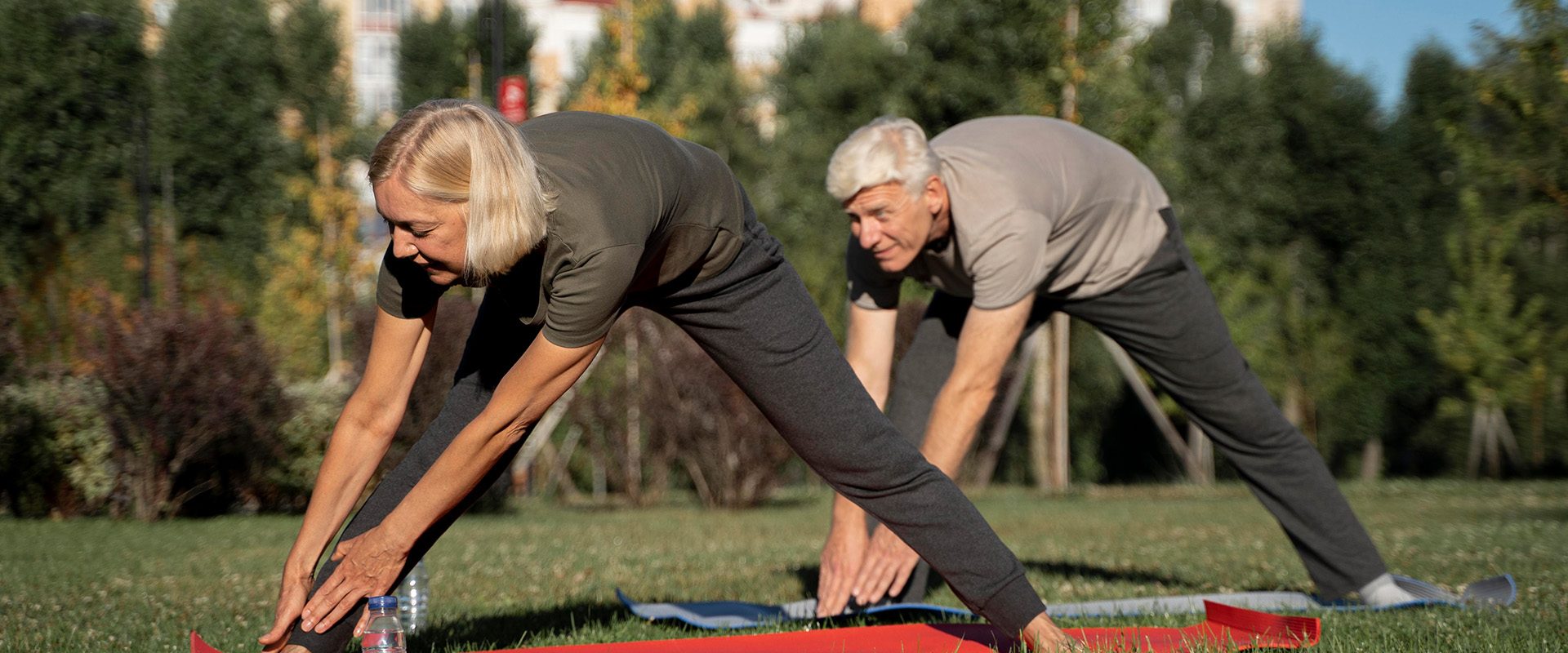 side-view-mature-couple-practicing-yoga-outdoors