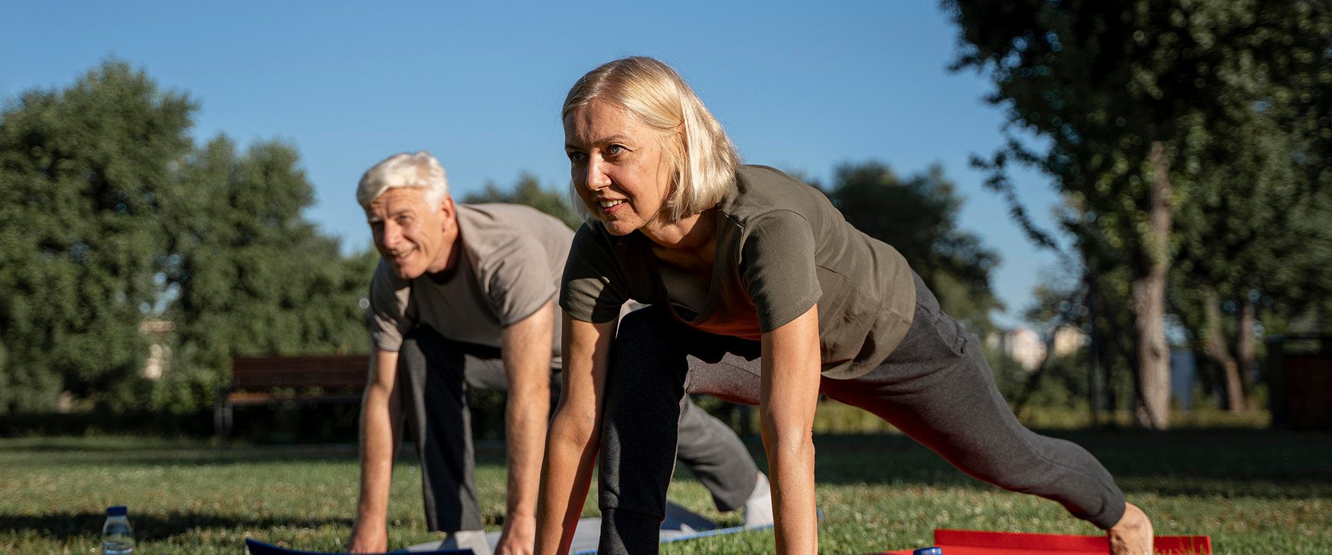 side-view-older-couple-practicing-yoga-outdoors